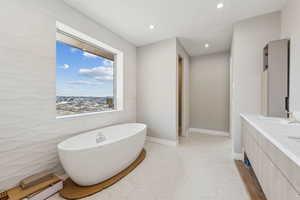 Bathroom featuring a baseboard heating unit, recessed lighting, a freestanding tub, tile patterned floors, and a sink