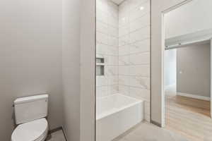 Bathroom featuring toilet, baseboards, and wood finished floors