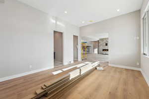 Interior space with light wood finished floors, recessed lighting, a large fireplace, and baseboards