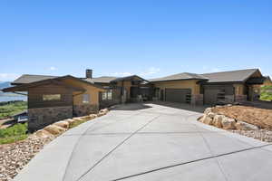 Prairie-style house featuring stone siding, a garage, concrete driveway, and a chimney