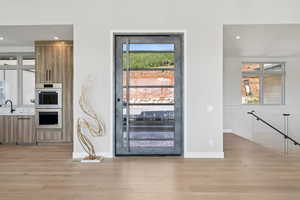 Kitchen featuring modern cabinets, light wood-style floors, brown cabinets, double oven, and recessed lighting