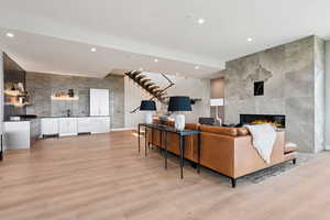 Living room with recessed lighting, light wood-type flooring, stairway, and a tiled fireplace