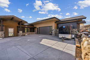 View of front of home featuring stone siding, an attached garage, and driveway