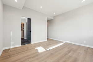 Unfurnished bedroom featuring a spacious closet, recessed lighting, baseboards, and light wood finished floors