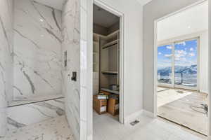 Bathroom with a marble finish shower and baseboards