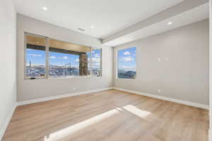 Spare room featuring a wealth of natural light, light wood-type flooring, and baseboards