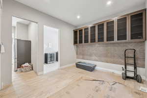 Kitchen with visible vents, wood finished floors, recessed lighting, glass insert cabinets, and baseboards