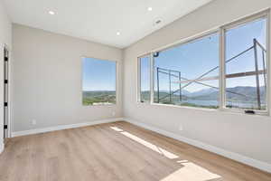 Unfurnished room with light wood-style floors, recessed lighting, and a water and mountain view