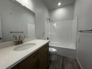 Full bathroom with vanity, shower / washtub combination, hardwood / wood-style flooring, and toilet