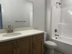 Full bathroom featuring hardwood / wood-style floors, washtub / shower combination, toilet, and vanity