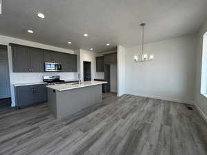 Kitchen featuring sink, an island with sink, hardwood / wood-style floors, and stainless steel appliances