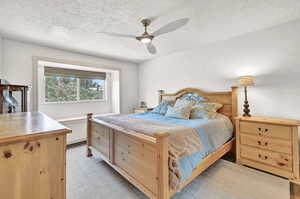 Primary bedroom with a textured ceiling and ceiling fan