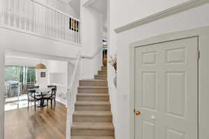 Stairs featuring wood-style LVT flooring and a towering ceiling