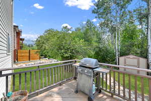 Deck with a lawn, a grill, and a shed