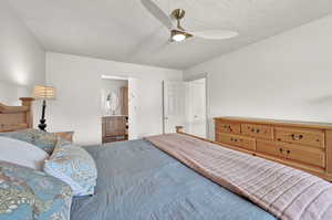 Primary Bedroom with ensuite bath, a textured ceiling, and ceiling fan