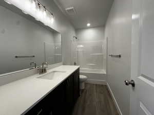 Full bathroom with vanity, shower / washtub combination, wood-type flooring, and toilet