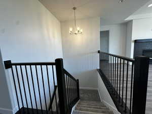 Stairs with carpet flooring and a notable chandelier