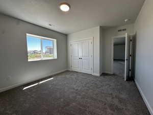 Unfurnished bedroom with carpet flooring, a closet, and a textured ceiling