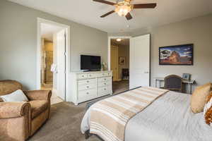 Bedroom featuring light carpet, ensuite bathroom, and ceiling fan