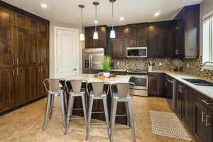 Kitchen with stainless steel appliances, sink, a kitchen island, decorative backsplash, and light tile patterned flooring