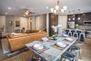 Dining room with ceiling fan with notable chandelier and light tile patterned floors