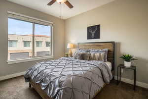 Bedroom featuring dark carpet, multiple windows, and ceiling fan