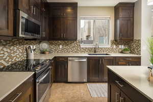 Kitchen with sink, tasteful backsplash, stainless steel appliances, and dark brown cabinets