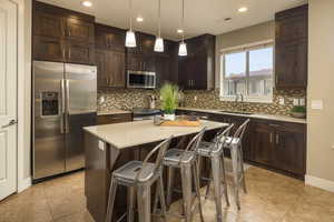 Kitchen with appliances with stainless steel finishes, backsplash, a center island, and sink