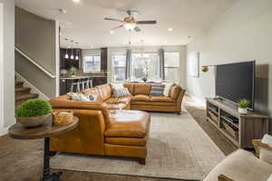 Living room featuring ceiling fan with notable chandelier, light colored carpet, and a textured ceiling