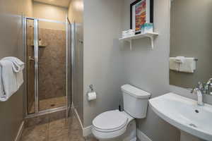 Bathroom featuring sink, toilet, and an enclosed shower