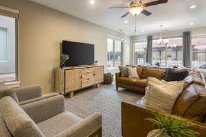 Living room featuring ceiling fan with notable chandelier