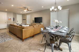 Tiled living room with ceiling fan with notable chandelier