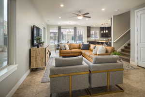 Living room with sink, light tile patterned flooring, and ceiling fan with notable chandelier