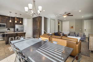 Tiled dining area featuring ceiling fan with notable chandelier