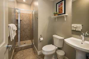 Bathroom featuring tile patterned flooring, a shower with door, toilet, and sink