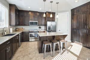 Kitchen with a center island, sink, dark brown cabinetry, a breakfast bar area, and stainless steel appliances