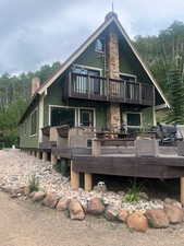 Rear view of house featuring a chimney, a balcony, and a deck
