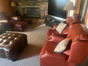 Carpeted living room featuring a stone fireplace