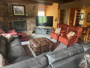 Carpeted living area with wooden walls and a stone fireplace