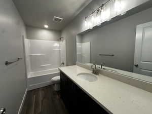 Full bathroom with shower / bathtub combination, a textured ceiling, toilet, vanity, and hardwood / wood-style flooring