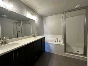 Bathroom featuring dual vanity, a textured ceiling, tile patterned flooring, and separate shower and tub