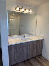 Bathroom with hardwood / wood-style floors, vanity, and an enclosed shower