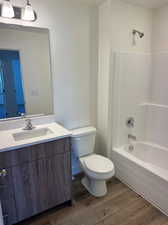 Full bathroom featuring wood-type flooring, shower / bath combination, toilet, and vanity