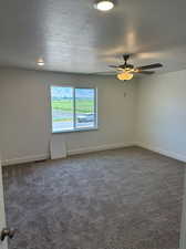 Carpeted spare room with a textured ceiling and ceiling fan