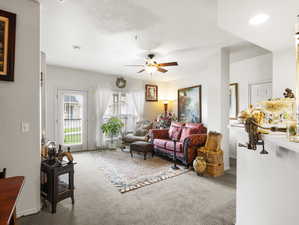 Carpeted living room with ceiling fan