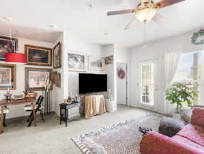 Living room featuring carpet floors, ceiling fan, and a healthy amount of sunlight