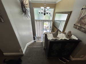 Interior space featuring an inviting chandelier, tile patterned floors, and ornamental molding