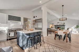 Kitchen featuring white cabinets, hanging light fixtures, lofted ceiling, and high end appliances