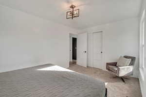 Bedroom #2. Main level. Furnished bedroom with light colored carpet, an inviting chandelier, and a closet