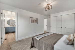 Master bedroom with hardwood / wood-style flooring, a notable chandelier, a closet, and ensuite bath